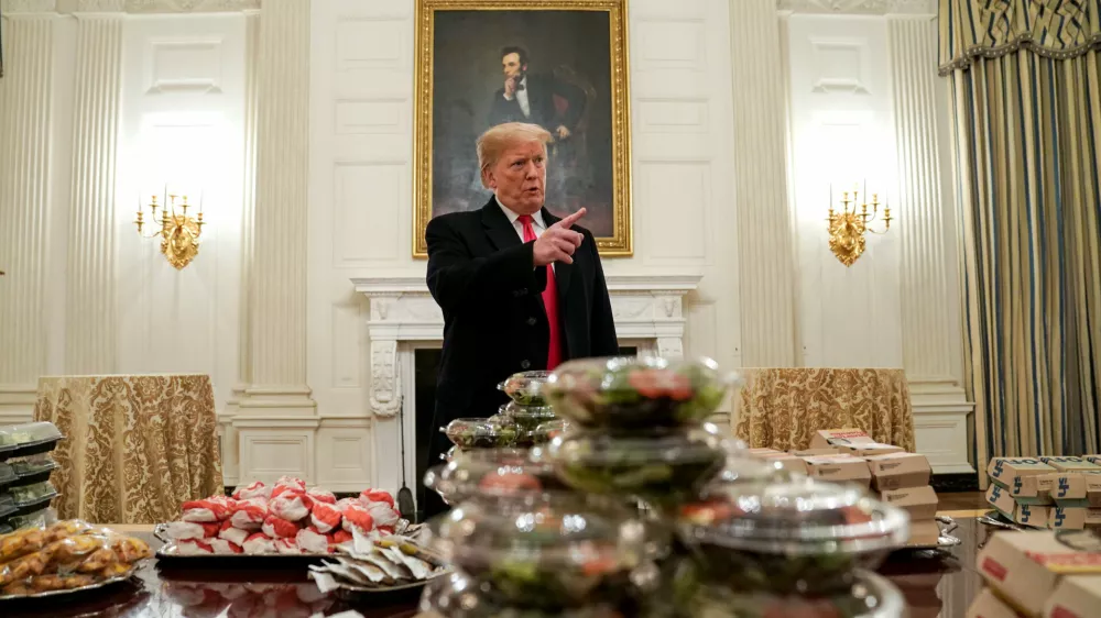 U.S. President Donald Trump speaks in front of fast food provided for the 2018 College Football Playoff National Champion Clemson Tigers due to the partial government shutdown in the State Dining Room of the White House in Washington, U.S., January 14, 2019.   REUTERS/Joshua Roberts   TPX IMAGES OF THE DAY