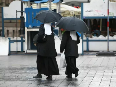 Nuni z dežniki na sprehodu po Zagrebu. 
