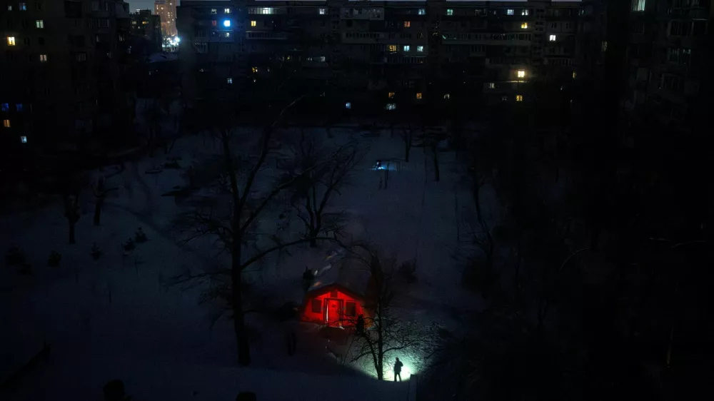 A person carrying a torch approaches a tent provided by emergency services for residents whose apartments are left without heating during sub-zero temperatures, amid Russia's attack on Ukraine, during a winter night in Kyiv, Ukraine, January 17, 2026. REUTERS/Thomas Peter    TPX IMAGES OF THE DAY