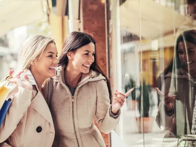 Women in shopping. Two happy women with shopping bags enjoying in shopping, having fun in the city. Consumerism, shopping, lifestyle concept