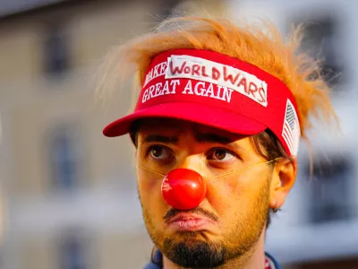 A man dressed as a clown waits for the start of a demonstration against President Trump and the Annual Meeting of the World Economy Forum in Davos, Switzerland, Sunday, Jan. 18, 2026. (AP Photo/Markus Schreiber)