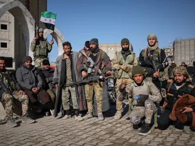 Tribal fighters pose for photographs taken by onlookers after Syrian government troops, supported by allied tribal forces, took control of Raqqa from the Syrian Democratic Forces (SDF) last Sunday at Al-Naeem roundabout in central Raqqa, northeastern Syria, Tuesday, Jan. 20, 2026. (AP Photo/Ghaith Alsayed)