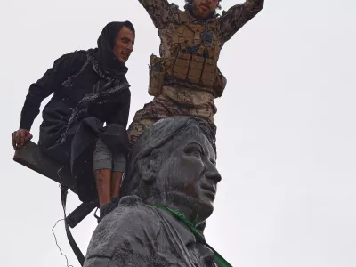 FILE - Syrian government soldiers wave a Syrian flag after climbing atop a statue of a female Kurdish fighter, following the takeover of the town from U.S.-backed Syrian Democratic Forces (SDF) during an ongoing push against Kurdish-led forces, in Tabqa, eastern Syria, Jan. 18, 2026. (AP Photo/Omar Albam, File)
