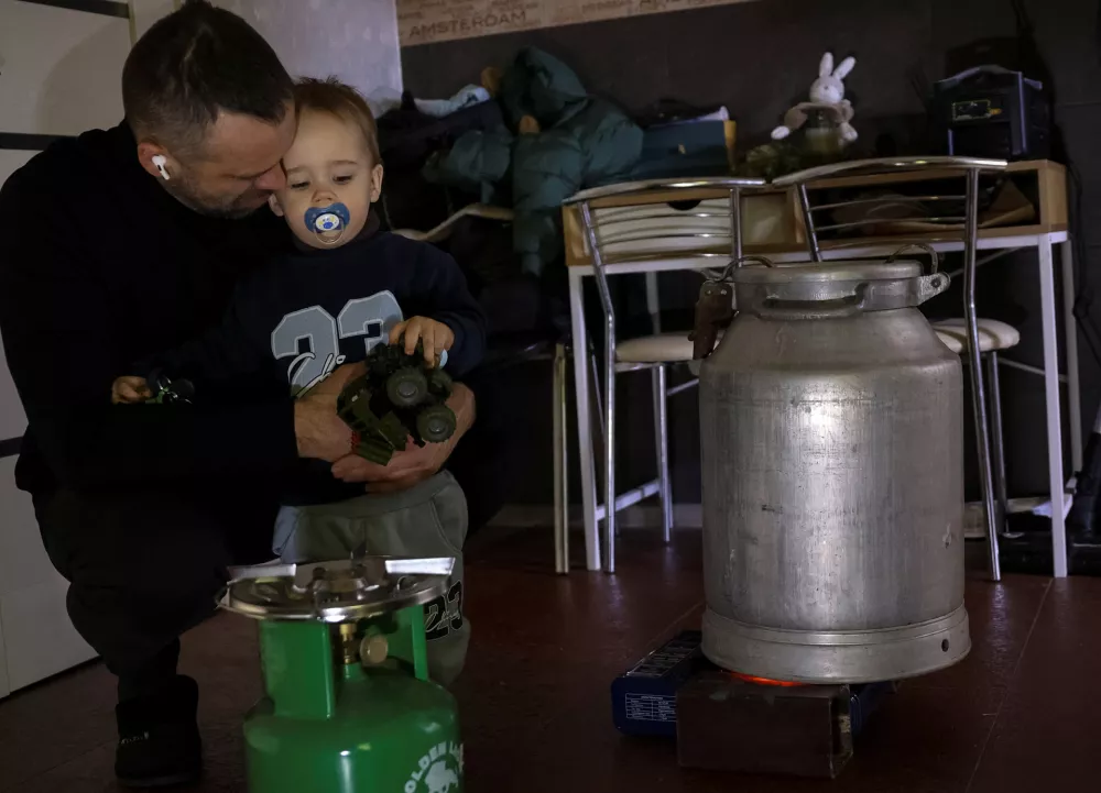 The military chaplain Anton Rybikov, 39, hugs his two-year-old son Matvii as he heats a metal churn with water, trying to warm his apartment during a power blackout after critical civil infrastructure was hit by recent Russian missile and drone attacks, amid Russia's attack on Ukraine, in Kyiv, Ukraine January 18, 2026. REUTERS/Anatolii Stepanov