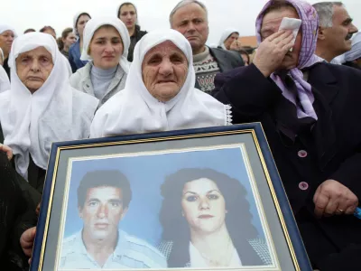 Relatives holding the pictures of their beloved ones weep during the burial of 30 Kosovo Albanians Friday Oct. 21, 2005, who were killed during the 1998-99 war between Serb forces and separatist guerrillas and buried in mass graves 350 kilometres north in Belgrade. The funeral took place in Kosovo Polje, just outside Kosovo's capital Pristina after the remains were returned from Serbia. (AP Photo/Visar Kryeziu)