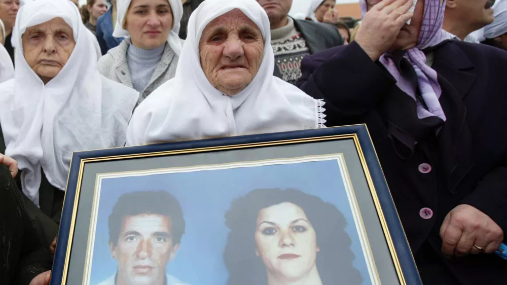 Relatives holding the pictures of their beloved ones weep during the burial of 30 Kosovo Albanians Friday Oct. 21, 2005, who were killed during the 1998-99 war between Serb forces and separatist guerrillas and buried in mass graves 350 kilometres north in Belgrade. The funeral took place in Kosovo Polje, just outside Kosovo's capital Pristina after the remains were returned from Serbia. (AP Photo/Visar Kryeziu)
