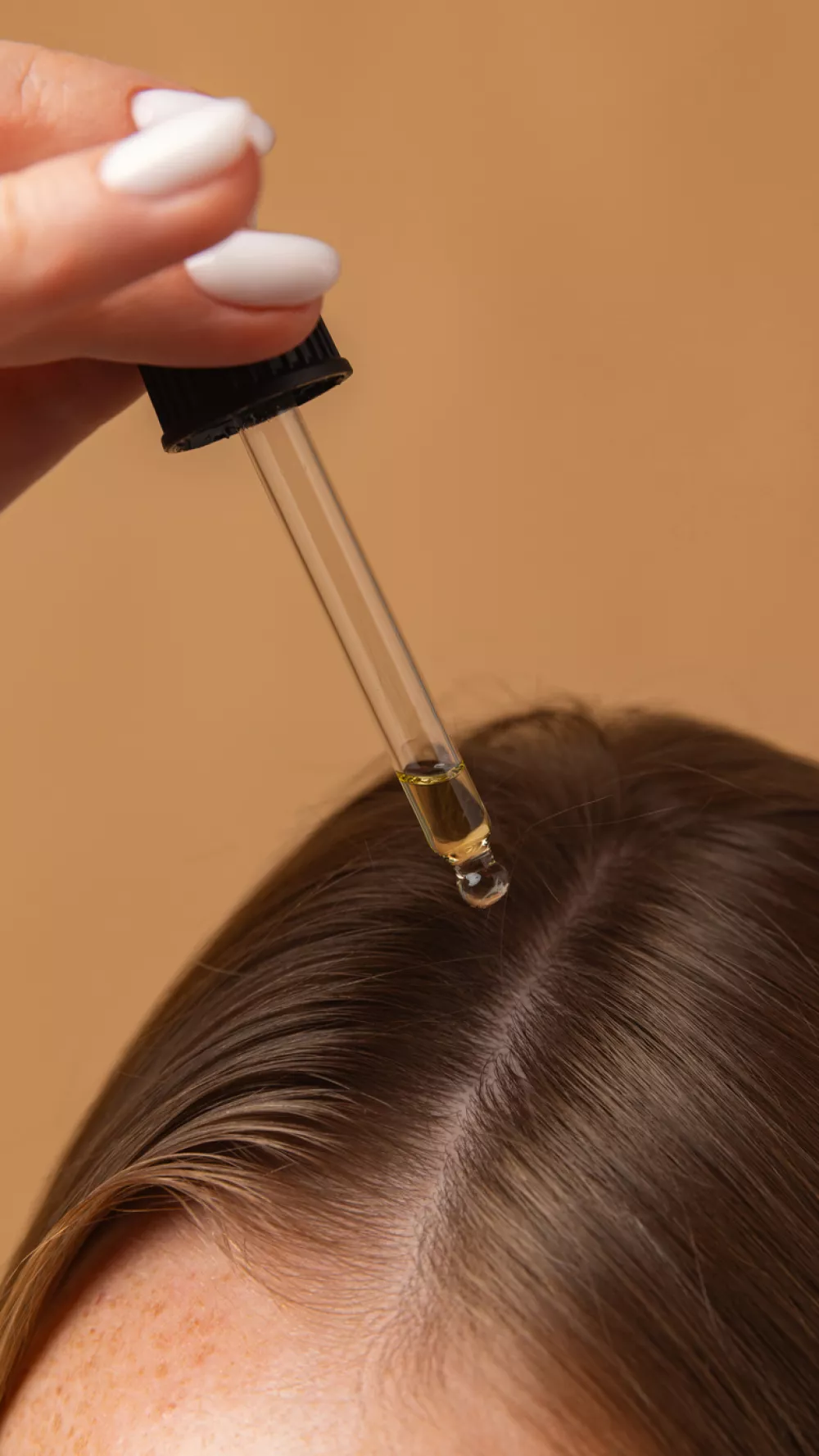Dropper applying nourishing oil to scalp for strengthening hair roots. Concept of scalp therapy, home wellness, trichology, and natural beauty care.