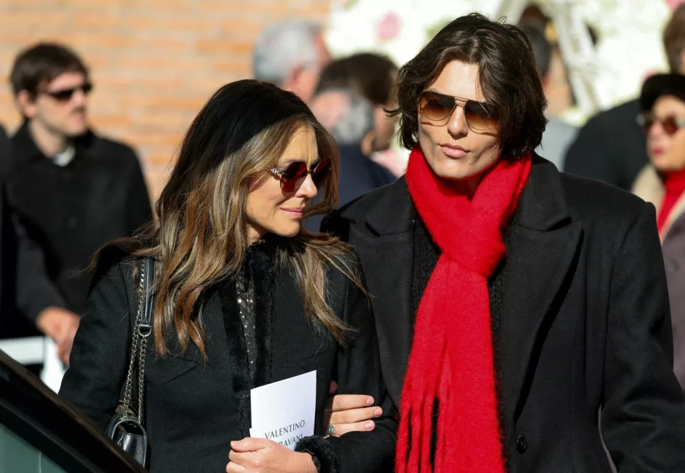 Actor Liz Hurley and her son Damian Hurley react next to the hearse carrying the coffin of the fashion designer Valentino Garavani, who died at the age of 93, outside the Basilica of Saint Mary of the Angels and Martyrs, during the funeral ceremony, in Rome, Italy, January 23, 2026. REUTERS/Yara Nardi