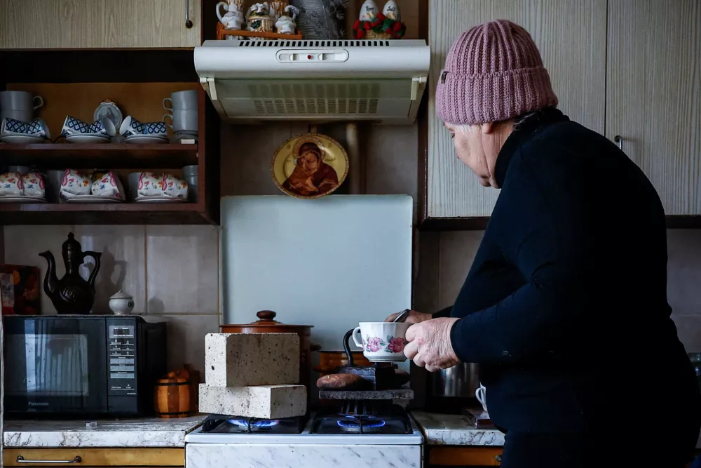 Liubov Klymenko, 66, heats fireproof bricks, stones and an old family iron on the stove in her kitchen, which she uses to warm her apartment after critical civil infrastructure was hit by recent Russian missile and drone strikes, amid Russia's attack on Ukraine, in Kyiv, Ukraine, January 23, 2026. REUTERS/Alina Smutko