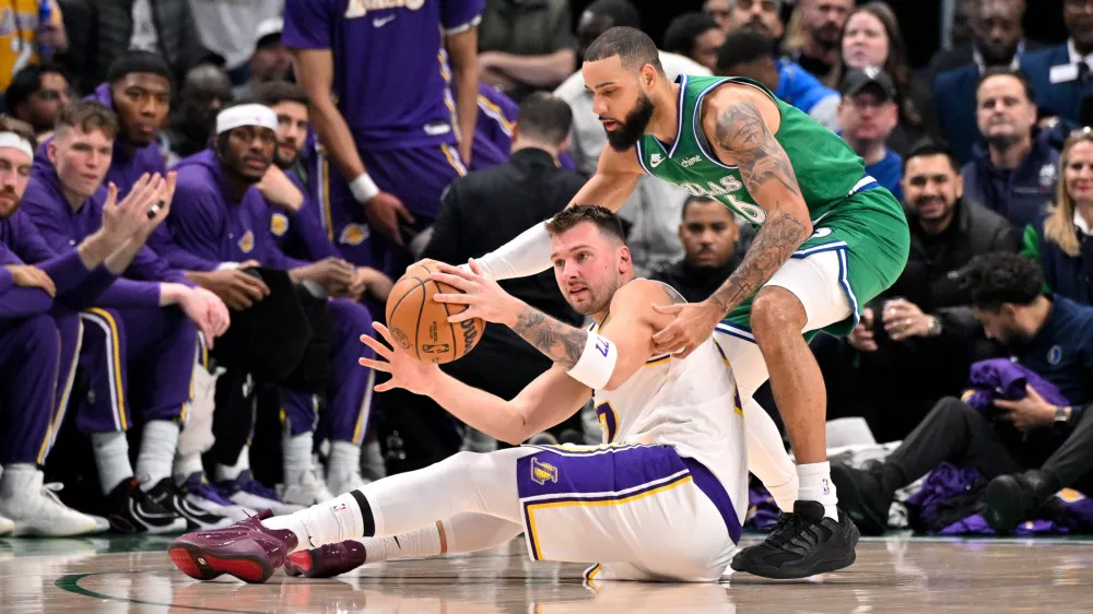 Jan 24, 2026; Dallas, Texas, USA; Los Angeles Lakers guard Luka Doncic (77) and Dallas Mavericks forward Caleb Martin (16) battle for control of the loose ball during the first quarter at the American Airlines Center. Mandatory Credit: Jerome Miron-Imagn Images