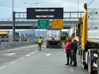 Men stand next to a line of trucks and buses on the Bosnian side of the border with Croatia, in Svilaj, Bosnia, Monday, Jan. 26, 2026, as drivers across the Balkans blocked dozens of border crossings in the region in protest over newly introduced European Union entry regulations.(AP Photo/Eldar Emric)