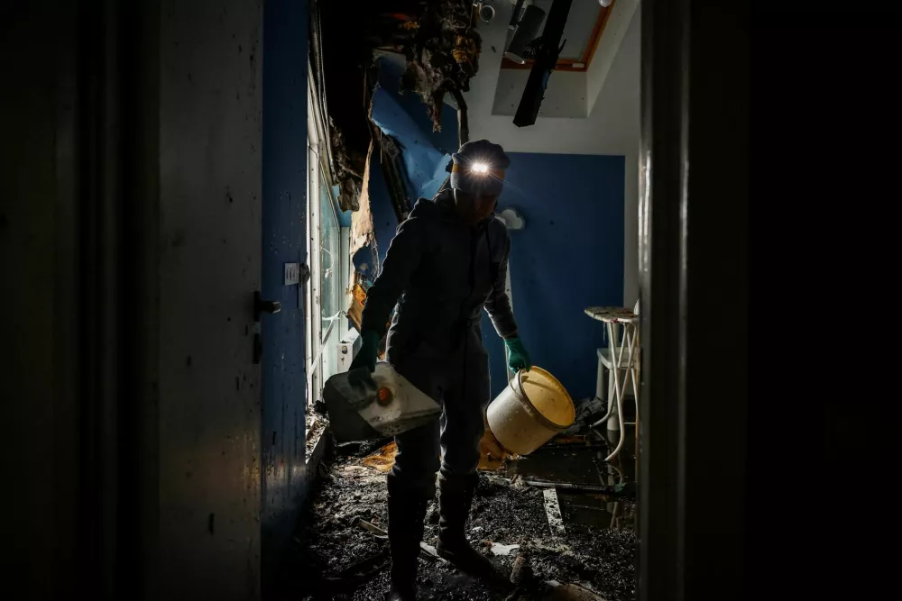 A woman cleans up the wreckage of a room at an apartment building, which was destroyed in the overnight Russian drone strikes, in the town of Bilohorodka, amid Russia's attack on Ukraine, in the Kyiv region, Ukraine, January 28, 2026. REUTERS/Alina Smutko