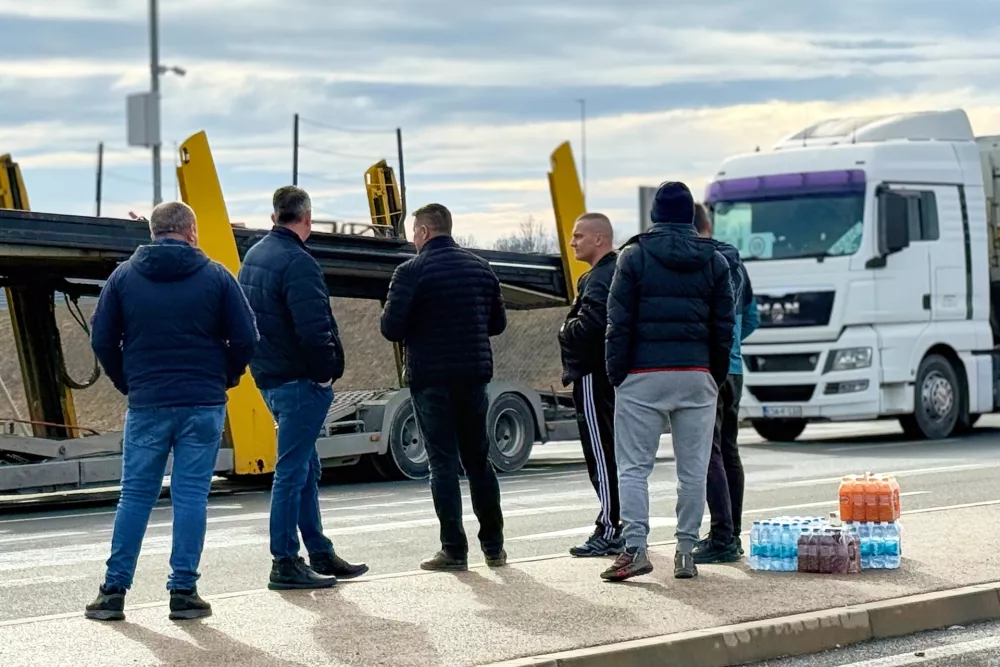 Men stand next to a line of trucks and buses on the Bosnian side of the border with Croatia, in Svilaj, Bosnia, Monday, Jan. 26, 2026, as drivers across the Balkans blocked dozens of border crossings in the region in protest over newly introduced European Union entry regulations.(AP Photo/Eldar Emric)