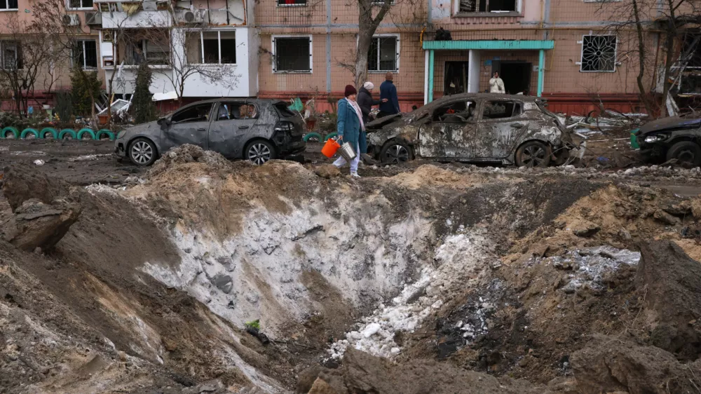People pass a crater and damaged cars near an apartment building after a Russian attack in Zaporizhzhia, Ukraine, Wednesday, Jan. 28, 2026. (AP Photo/Kateryna Klochko)
