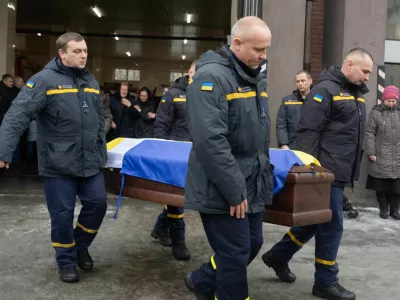 Rescuers carry the coffin of their fellow Oleksandr Zibrov, 36, who was killed in a secondary Russian drone strike on a residential building, at a fire station in Kyiv, Ukraine, Wednesday, Jan. 28, 2026. (AP Photo/Efrem Lukatsky)