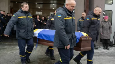 Rescuers carry the coffin of their fellow Oleksandr Zibrov, 36, who was killed in a secondary Russian drone strike on a residential building, at a fire station in Kyiv, Ukraine, Wednesday, Jan. 28, 2026. (AP Photo/Efrem Lukatsky)