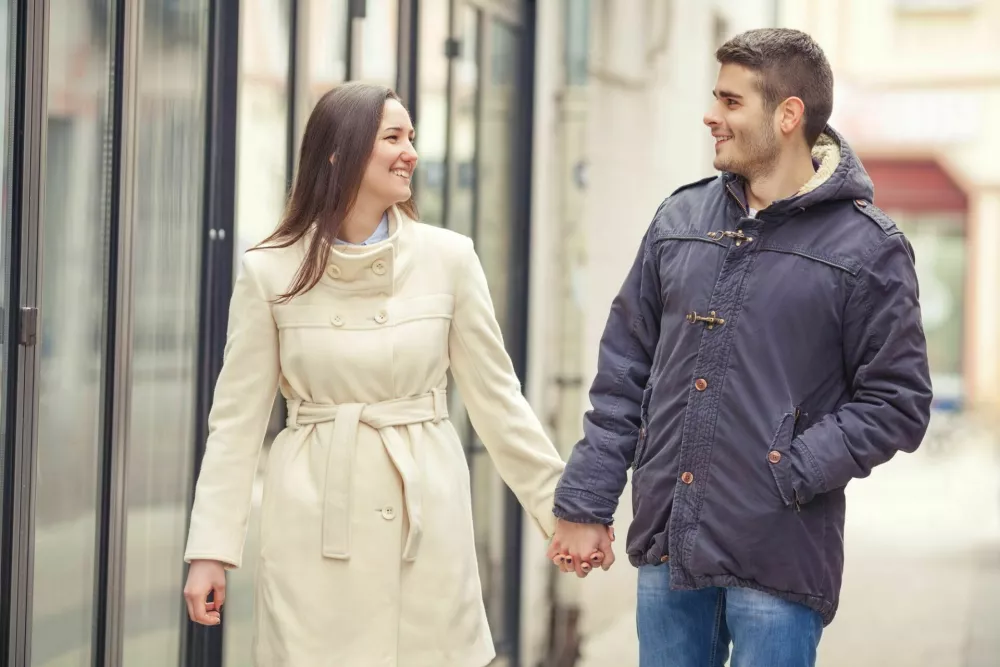 Happy young couple walking around the city holding hands and looking at each other / Foto: Bokan76