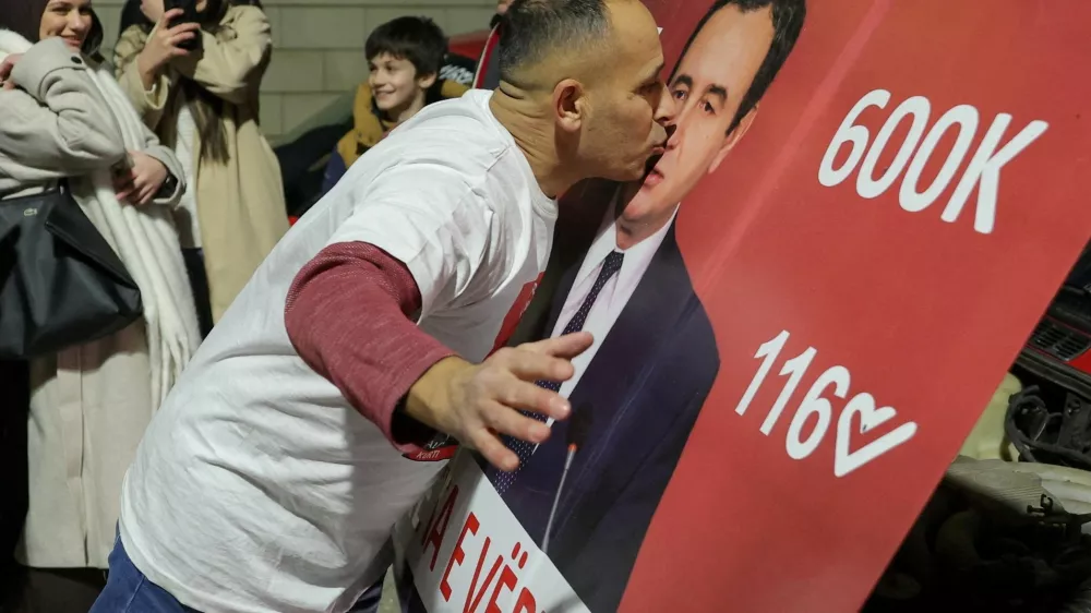 A man kisses a hood of a car with an image of Kosovo's Prime Minister and Levizja Vetevendosje (Movement for Self-Determination) party leader Albin Kurti, as the party leads in early vote results, on the day of a snap parliamentary election, nearly a year after a political deadlock that prevented the formation of a new government, in Pristina, Kosovo, December 28, 2025. REUTERS/Valdrin Xhemaj REFILE - CORRECTING INFORMATION FROM "KISSES A POSTER" TO "KISSES A HOOD OF A CAR".