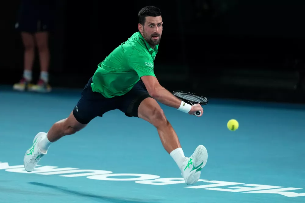 Novak Djokovic of Serbia plays a backhand return to Jannik Sinner of Italy during their semifinal match at the Australian Open tennis championship in Melbourne, Australia, Friday, Jan. 30, 2026. (AP Photo/Dita Alangakra)