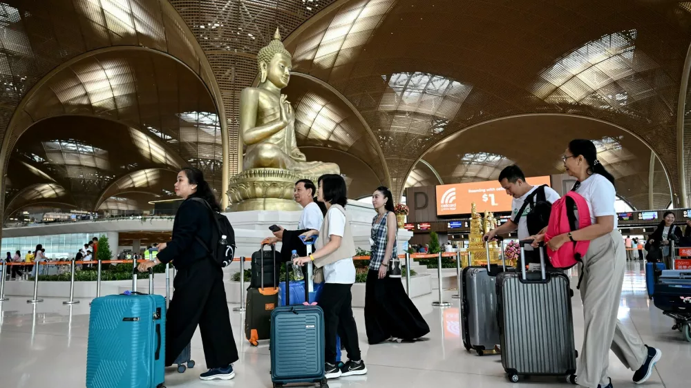 Passengers walk with their luggage past a statue of Buddha on the inauguration day of the newly built Techo International Airport in Kandal province, on the outskirts of Phnom Penh, on September 9, 2025. A new major airport serving the capital Phnom Penh began operations.,Image: 1035477357, License: Rights-managed, Restrictions:, Model Release: no