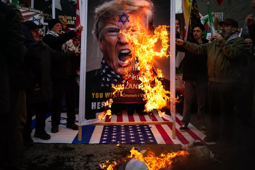 Protesters burn a poster of President Donald Trump during an anti-U.S. and anti-Israeli rally in support of the Iranian government, outside the U.S. consulate in Istanbul, Sunday, Feb. 1, 2026. (AP Photo/Emrah Gurel)