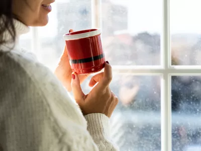 A girl drinks a cup of coffee on a cold day. Relaxed day at home in Christmas time. / Foto: Rolart Studio, Getty Images