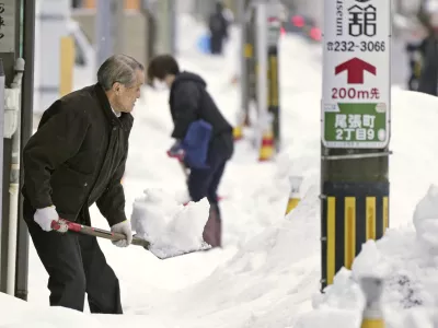 Residents shovel snow off a sidewalk in Kanazawa, Ishikawa prefecture, central Japan, on Dec. 24, 2022. (Kyodo News via AP)