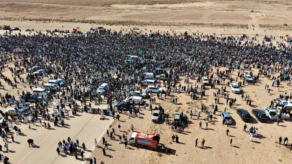 Thousands of Libyans crowd to attend the funeral of Seif al-Islam, son of former Libyan Leader Moammar Gadhafi, as they hold a poster of his father in Bani Walid city, Libya, Friday, Feb. 6, 2026. (AP Photo/Yousef Murad)