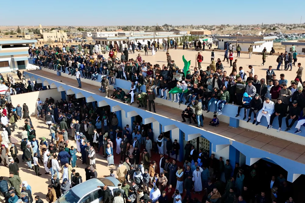 Libyans crowd to attend the funeral of Seif al-Islam, son of former Libyan Leader Moammar Gadhafi, as they hold a poster of his father in Bani Walid city, Libya, Friday, Feb. 6, 2026. (AP Photo/Yousef Murad)