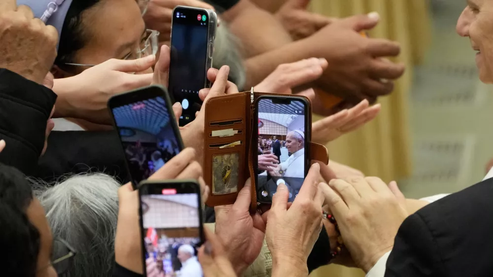 Faithful use their phones to take pictures as they try to reach for Pope Leo XIV hands at the end of the weekly general audience at the Vatican, Wednesday, Feb. 11, 2026. (AP Photo/Gregorio Borgia) / Foto: Gregorio Borgia