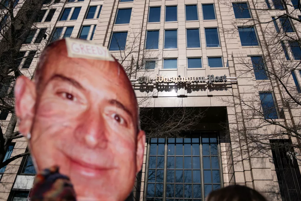 A protester holds a cutout of Jeff Bezos' face outside of the Washington Post office following a mass layoff, Thursday, Feb. 5, 2026, in Washington. (AP Photo/Allison Robbert)