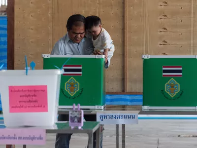 08 February 2026, Thailand, Bangkok: A man hoding a kid casts his ballot at a polling station during the general elections in Bangkok. Thailand's 53 million eligible voters are to elect a new parliament on Sunday, while also determining in a referendum whether to initiate the formation of a new national constitution. Photo: Peerapon Boonyakiat/SOPA Images via ZUMA Press Wire/dpa