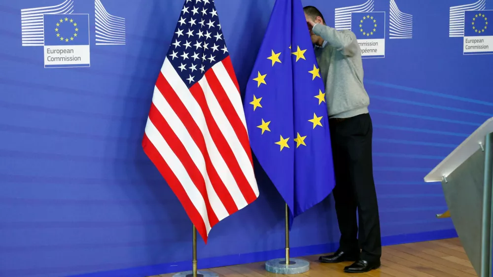FILE PHOTO: A worker adjusts European Union and U.S. flags at the EU Commission headquarters in Brussels, November 11, 2013./File Photo