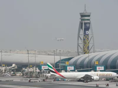 FILE - An Emirates Boeing 777 stands at the gate at Dubai International Airport as another prepares to land on the runway in Dubai, United Arab Emirates, Aug. 17, 2022. (AP Photo/Jon Gambrell, File)