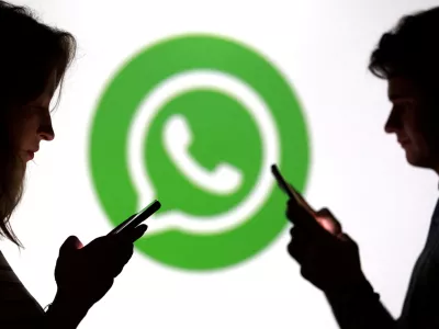 FILE PHOTO: Teenagers pose for a photo while holding smartphones in front of a Whatsapp logo in this illustration taken September 11, 2025. REUTERS/Dado Ruvic/Illustration/File Photo