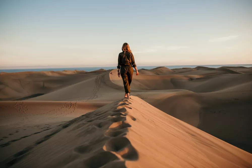 Aviator woman walking on dune