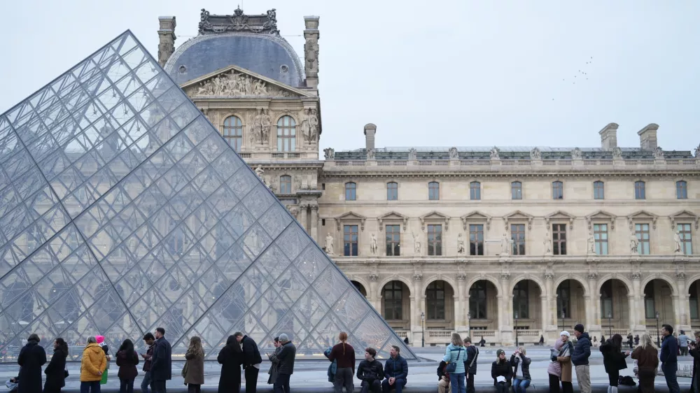 FILE - People wait for the Louvre museum to open as employees at the Louvre Museum vote to extend a strike that has disrupted operations at the world's most visited museum, Dec. 18, 2025 in Paris. (AP Photo/Thibault Camus, File)