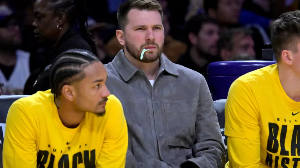 Feb 12, 2026; Los Angeles, California, USA; Los Angeles Lakers guard Luka Doncic (77) looks on from the bench as he chews on a dental flosser in the second half against the Dallas Mavericks at Crypto.com Arena. Mandatory Credit: Jayne Kamin-Oncea-Imagn Images