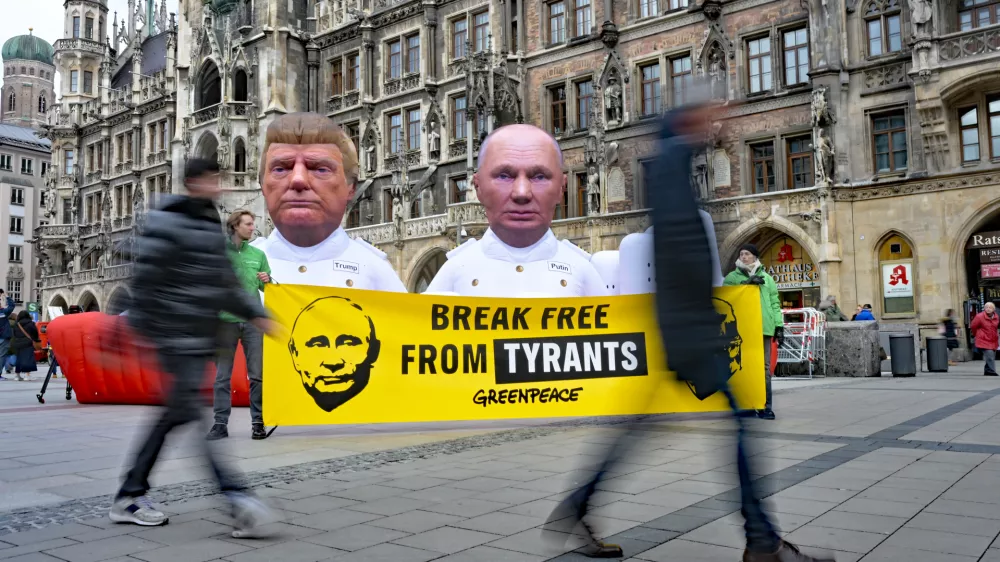 13 February 2026, Bayern, M&uuml;nchen: Greenpeace activists display giant sculptures of US President Donald Trump and Russian President Vladimir Putin standing on a 10-meter model gas tanker labeled "Fossil Gas" at Marienplatz in Munich. A banner reading "Break Free From Tyrants" accompanies the protest, marking the start of the Munich Security Conference. Photo: Malin Wunderlich/dpa