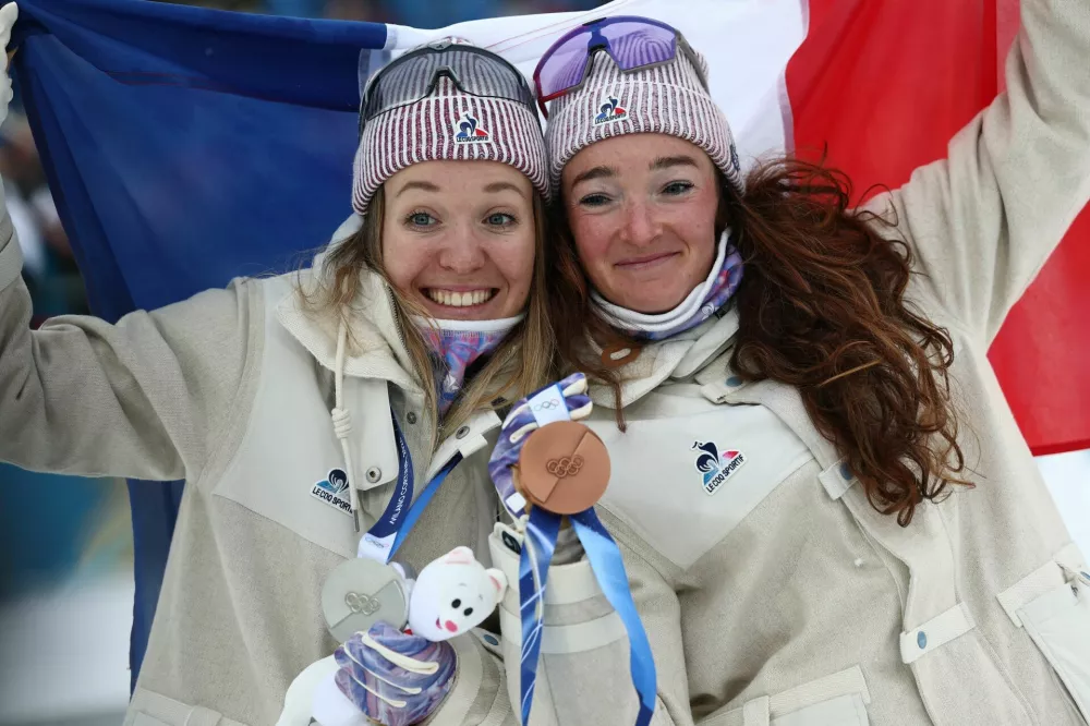 Milano Cortina 2026 Olympics - Biathlon - Women's 7.5km Sprint Victory Ceremony - Anterselva Biathlon Arena, South Tyrol, Italy - February 14, 2026. Silver medallist Oceane Michelon of France and Bronze medallist Lou Jeanmonnot of France celebrate with their medals and national flag during the presentation for the Women's 7.5km Sprint REUTERS/Eloisa Lopez