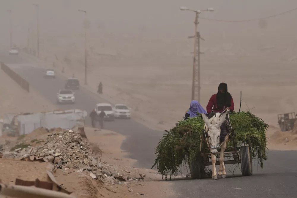 Palestinian women ride a donkey cart along the coastal road in Wadi Gaza during a dust storm in the central Gaza Strip, Saturday, Feb. 14, 2026. (AP Photo/Abdel Kareem Hana)