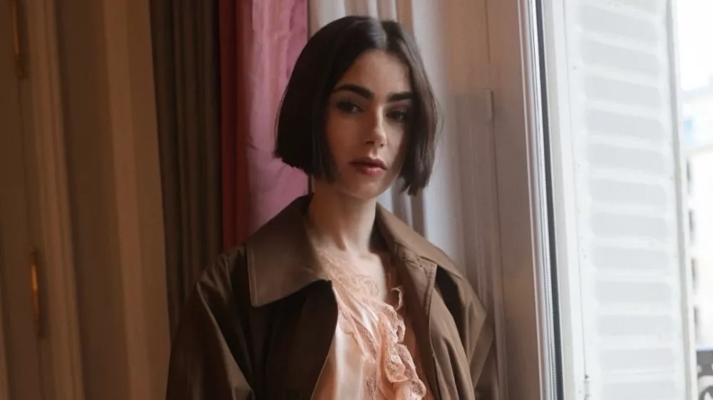 Minulo nedeljo je Lily Collins, ki v seriji Netflix Emily v Parizu igra glavno junakinjo, prispela v Pariz z vlakom Venice Simplon-Orient-Express in bila ujeta v objektivih med promocijo prihajajoče sezone. Nosila je drzen, blush toniran kos spodnjega perila, ki ga je Saint Laurent oblikoval Anthony Vaccarello, oblečenega skupaj s čokoladno rjavim trench pla&scaron;čem in usnjenim clutch torbico. Outfit velja za enega najbolj drznih, ki jih je Collins nosila doslej, &scaron;e posebej za igralko, katere osebni slog se običajno nagiba k klasični eleganci. Nova sezona Emily v Parizu bo na Netflixu na voljo 22. decembra 2025, kar bo priložnost, da gledalci ponovno vidijo Emily v drzni modni izbiri.