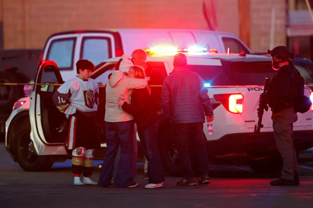 People embrace near a police officer outside the Dennis M Lynch Arena, an indoor ice skating rink, after a shooting in Pawtucket, Rhode Island, U.S., February 16, 2026. REUTERS/CJ Gunther