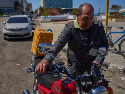 Retiree Jorge Reyes pushes his motorcycle to refuel as it's his turn in line at a gasoline station in Havana, Cuba, Monday, Feb. 16, 2026. (AP Photo/Ramon Espinosa)