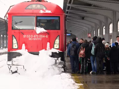 Passengers wait next to a snow covered train engine at the Gara de Nord railway station, after a blizzard in Bucharest, Romania, Wednesday, Feb. 18, 2026. (AP Photo/Vadim Ghirda)