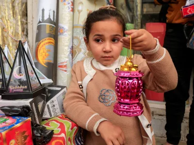 A Palestinian girl holds a Ramadan lantern at a market where seasonal decorations are sold, in Khan Younis in the southern Gaza Strip, February 14, 2026. REUTERS/Haseeb Alwazeer