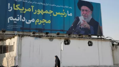 A woman walks past a billboard with an image of Iranian Supreme Leader Ayatollah Ali Khamenei with a quotation of him which says: "We recognise the President of America as a criminal," in Tehran, Iran, Tuesday, Feb. 17, 2026. (AP Photo/Vahid Salemi)