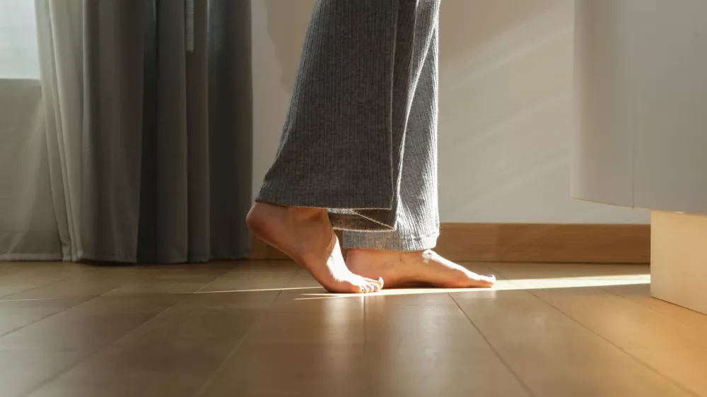 Barefoot woman on the wooden floor. Concept of the underfloor heating in the apartment.