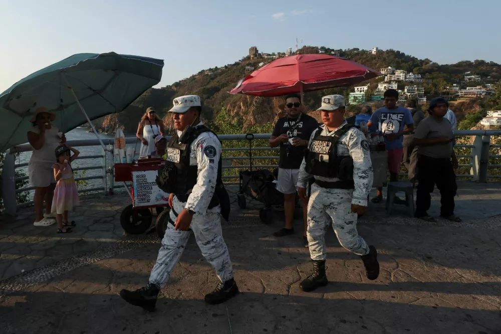 Members of the National Guard walk past people while on patrol, after authorities reinforced security following roadblocks and arson attacks carried out by organised crime in several states, in the aftermath of a military operation in which a government source said Mexican drug lord Nemesio Oseguera, known as "El Mencho," was killed in Jalisco state, in Acapulco, Mexico, February 22, 2026. REUTERS/Henry Romero