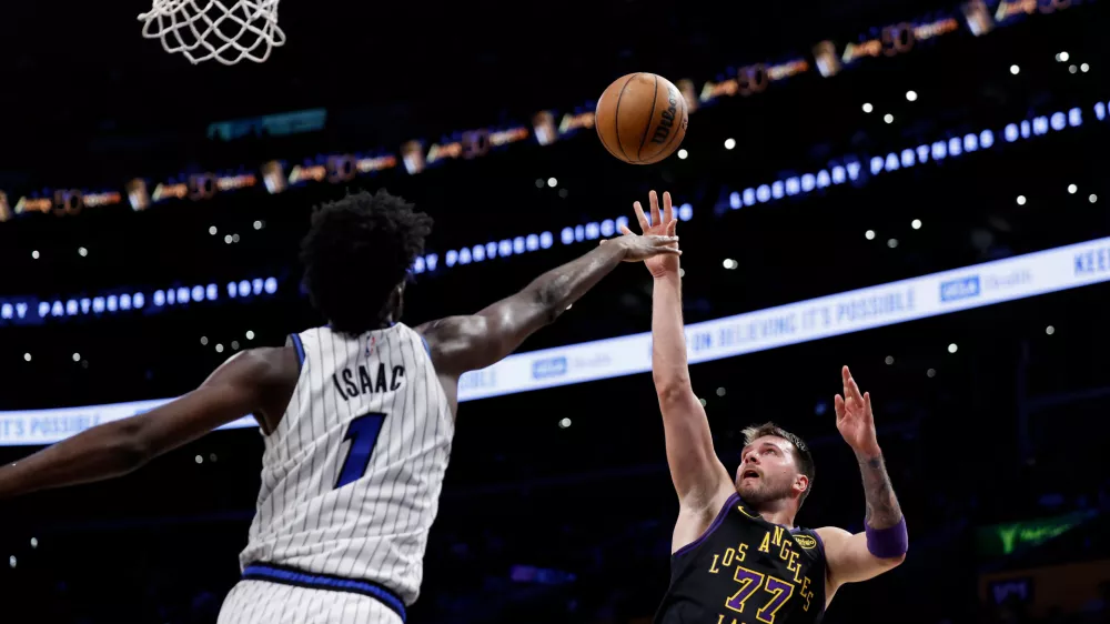Los Angeles Lakers guard Luka Doncic (77) shoots the ball while being guarded by Orlando Magic forward Jonathan Isaac (1) during the second half of an NBA basketball game Tuesday, Feb. 24, 2026, in Los Angeles. (AP Photo/Caroline Brehman)